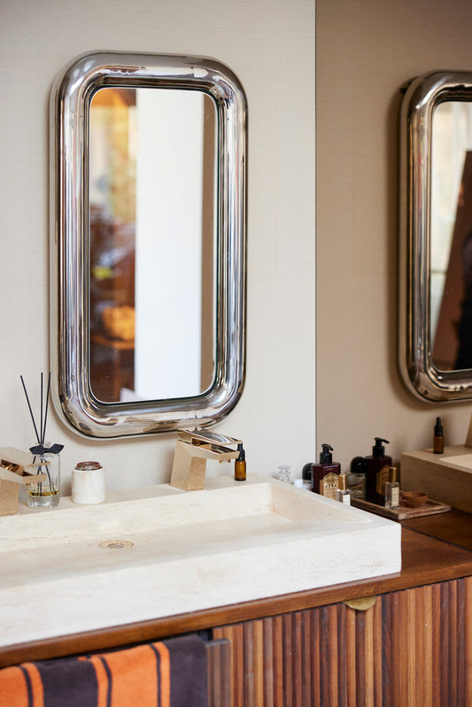 rectangular chrome chubby mirror in bathroom with orange and brown striped towel