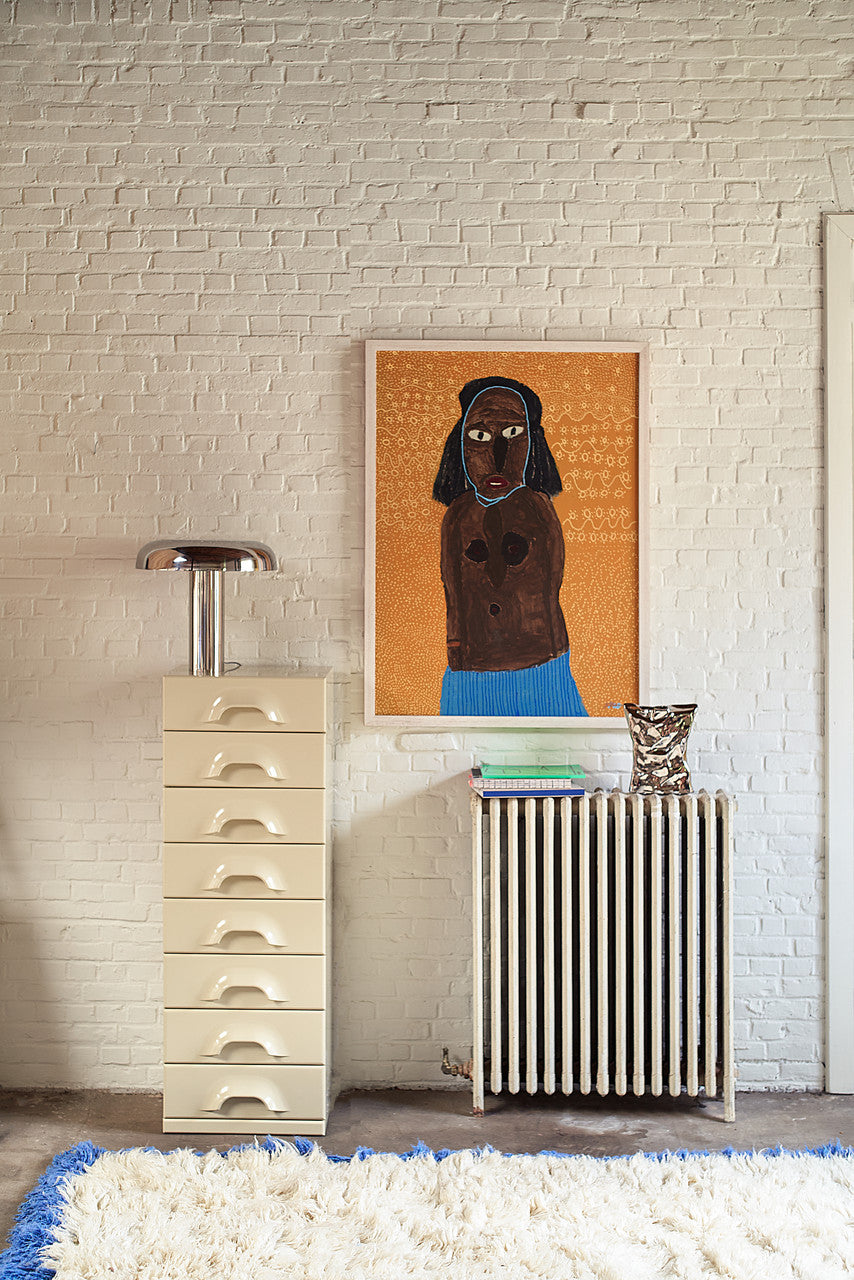 mushroom shape chrome colored table lamp on a drawer with an art work hanging next to it