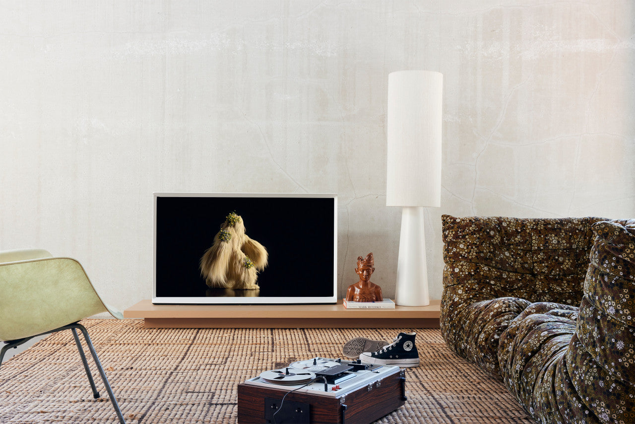 living room with flatscreen tv, jute rug and a large cream colored cone floor lamp