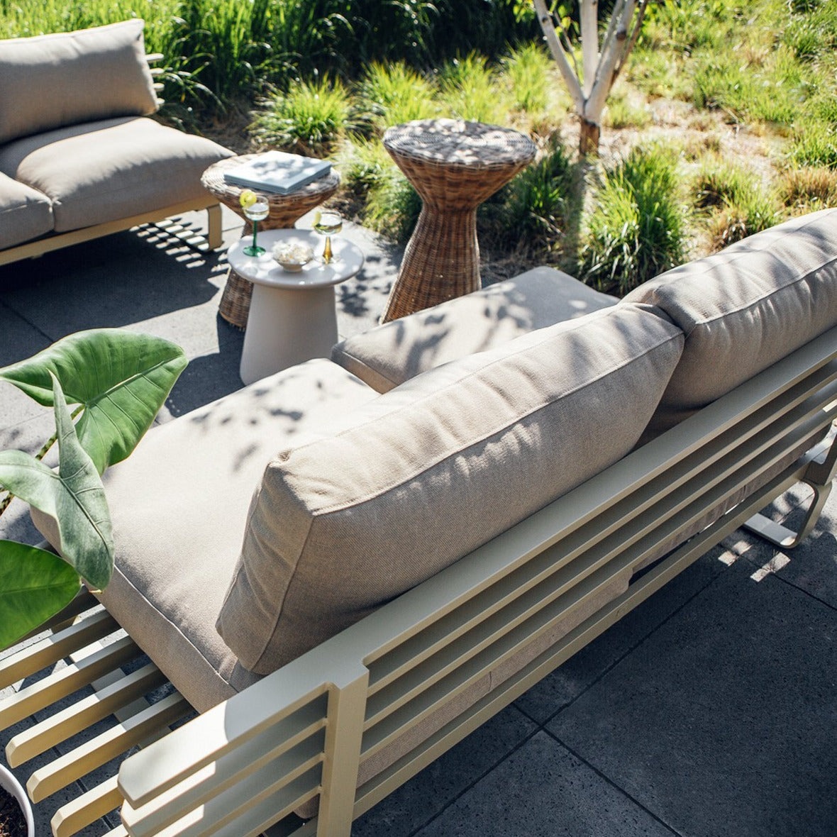 back  of olive colored aluminum sofa with beige pillows