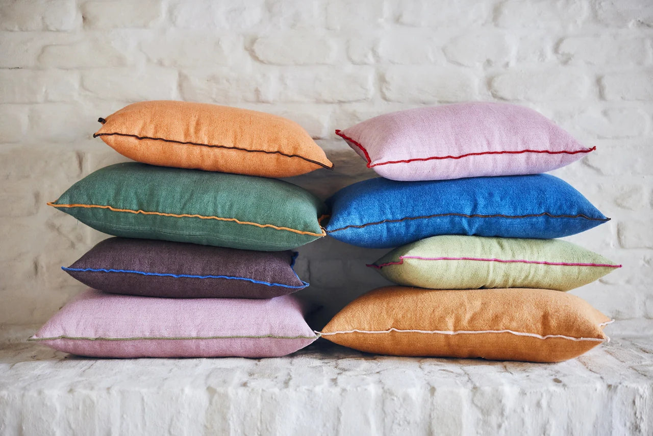 orange, green, purple, pink and blue linen pillows on a stack with contrasting cotton trim