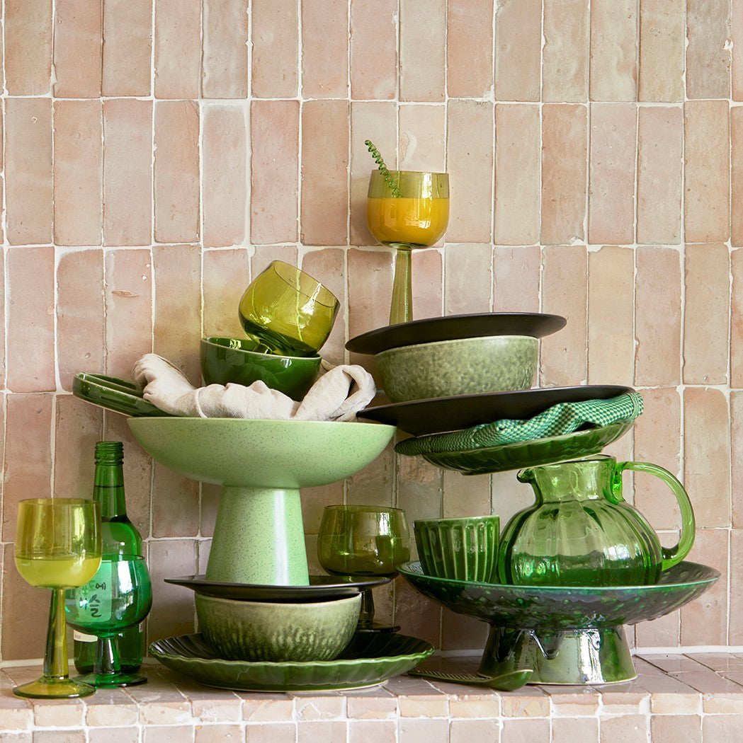 green plates, bowls and glasses stacked in a kitchen