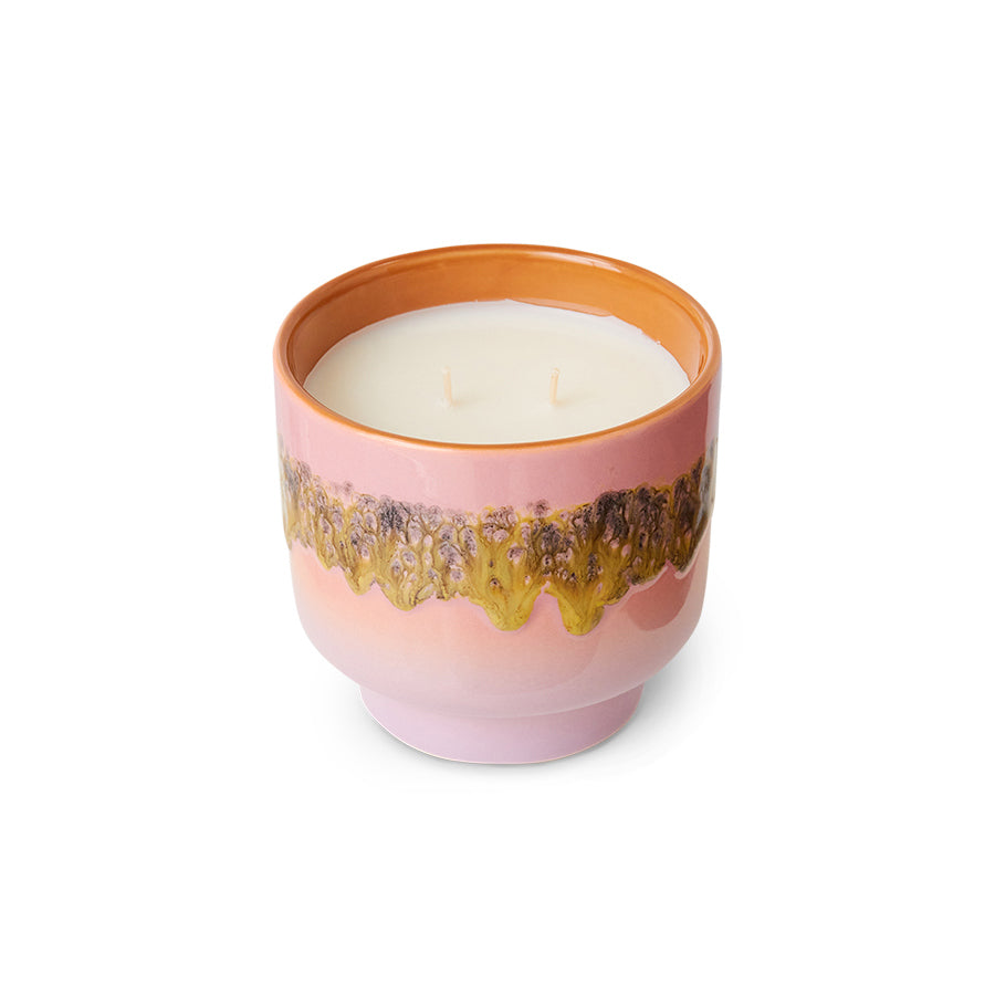 Candle in a pink container with gold decorative elements on a white background