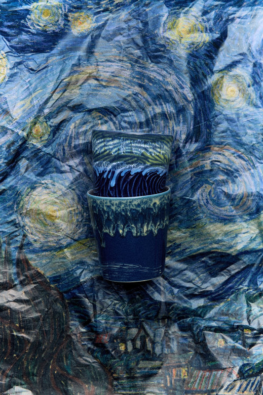 Two blue Cups  on a textured surface resembling 'Starry Night' by Van Gogh