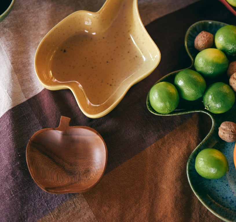 Half-cut papaya on a blue plate with limes and nuts on a brown textured surface