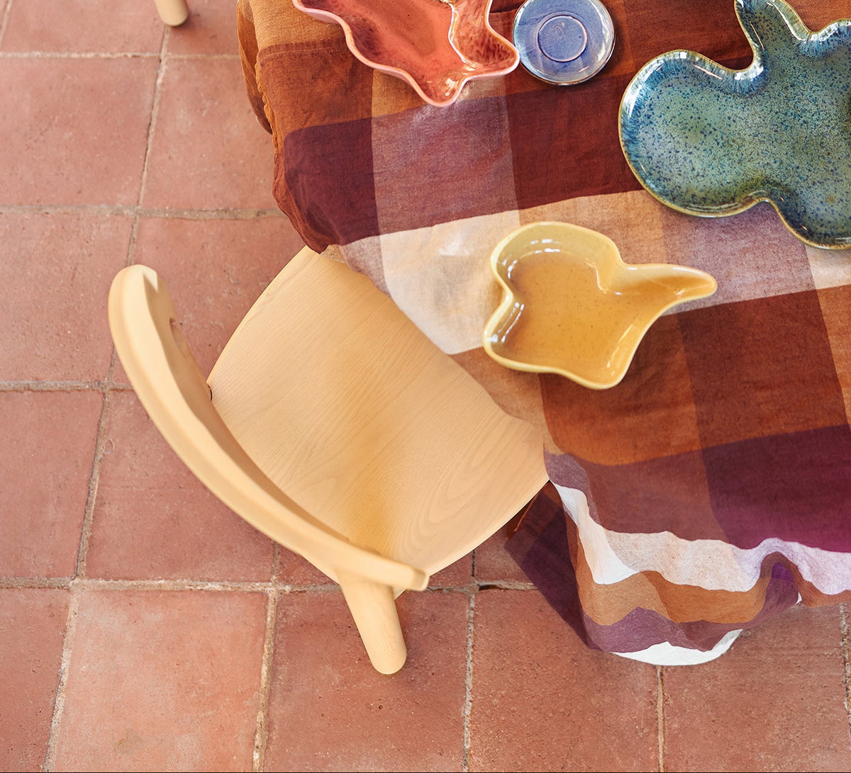 Round wooden table with colorful ceramic plates and cookie cutters on a tiled floor.