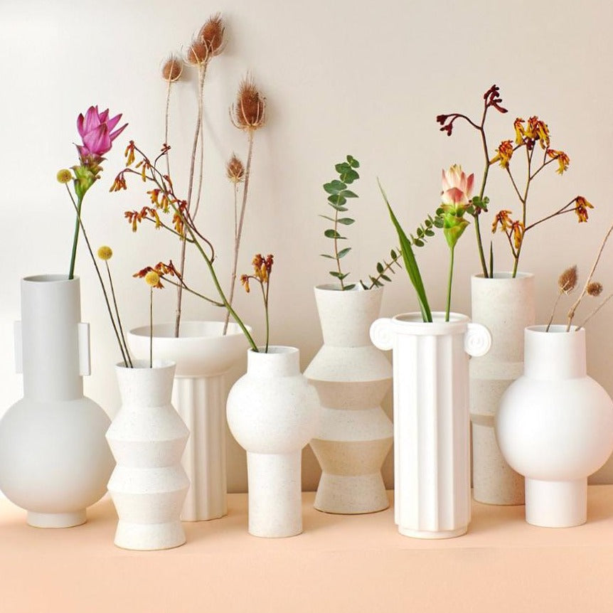 group of white speckled clay vases with spring flowers