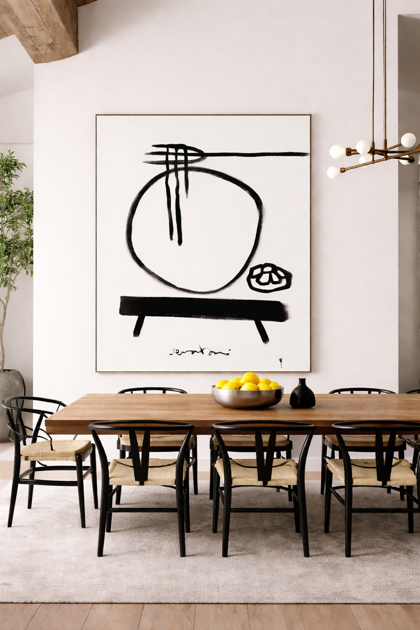 Dining room with a wooden table and chairs, abstract art on the wall, and a bowl of fruit.