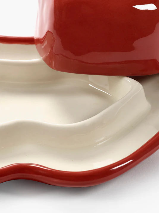 Close-up of a red and white ceramic dish set on a white background