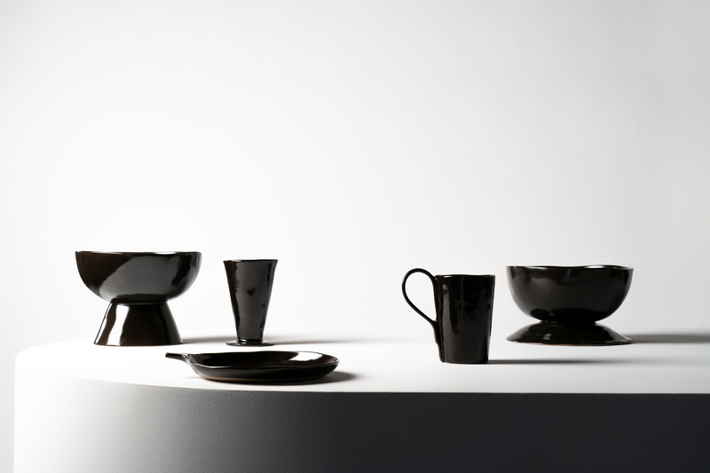 Black ceramic tableware set on a white surface with a white background