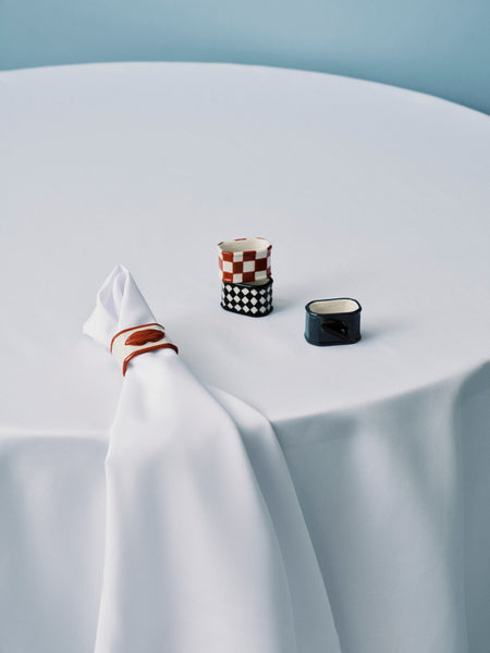 Two small ceramic containers on a white tablecloth with a light blue background