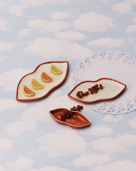 Three mount ceramic plates with fruit and berry decorations on a cloud-patterned background