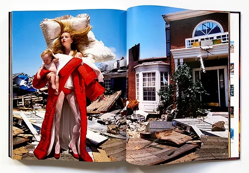 Open book showing a woman in a red outfit holding a baby amidst destruction, with a normal house on the right.