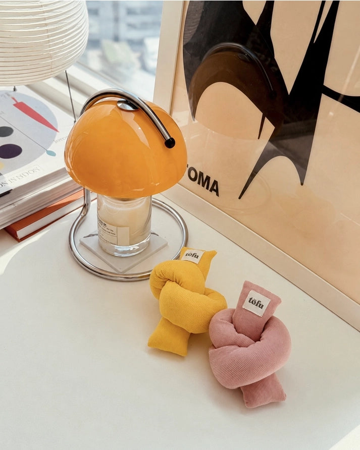 two knotted design toys on a white table with a yellow lamp