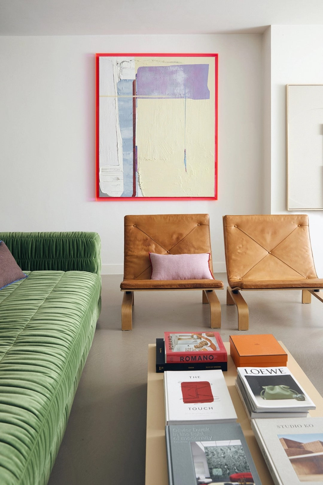 green sofa, coffee table with photobooks, brown chairs and abstract painting on canvas with neon acrylic frame
