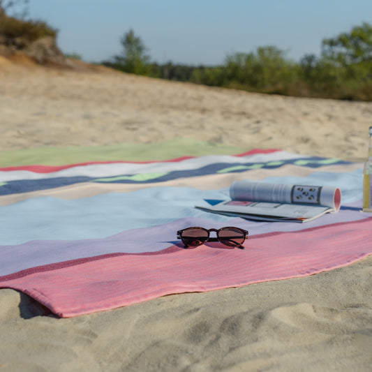 striped beach blanket with sunglasses and a book
