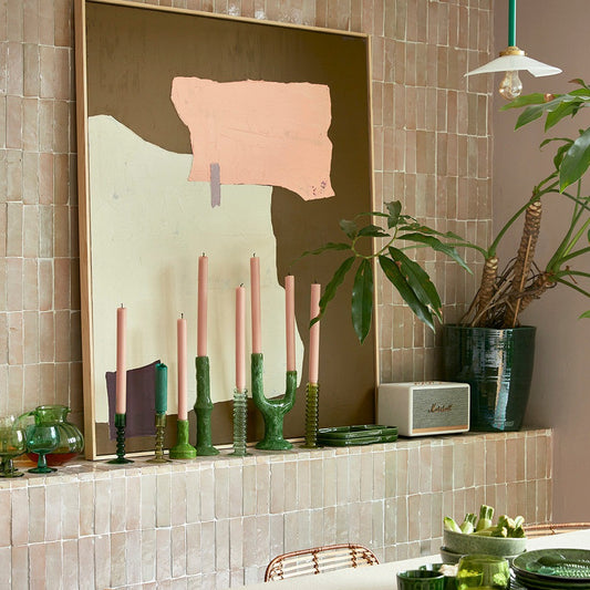 large abstract painting and green glass and stoneware candle stick holders with pink candles