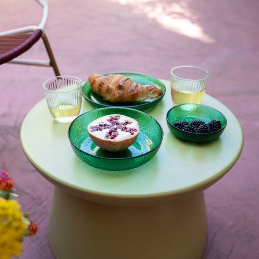 geen side table with green glass tableware and fruit and croissant