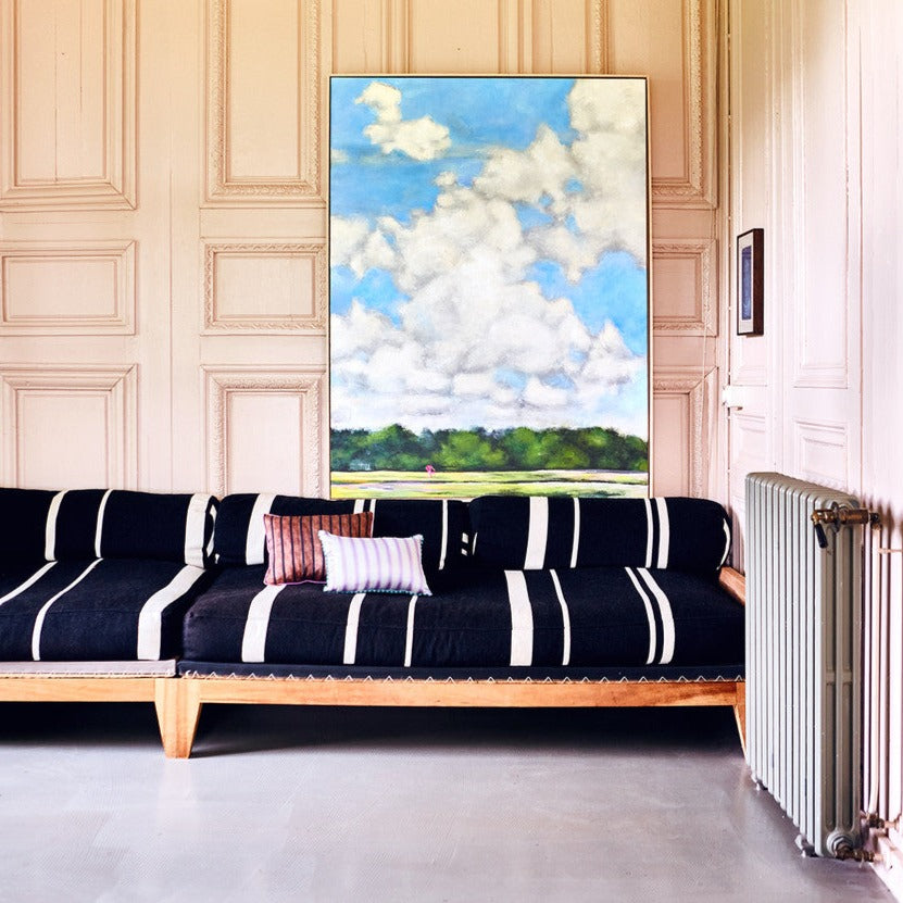 marine blue and white striped sofa with silk pillows and large painting of Dutch landscape on wall