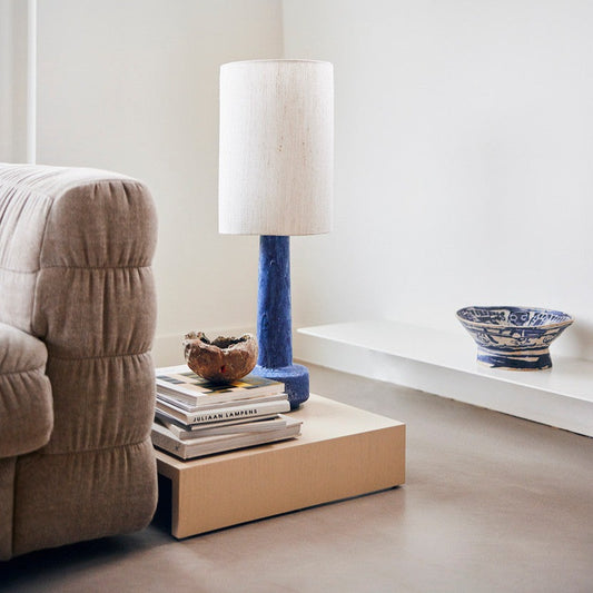 taupe colored  linen sofa, low wooden side table and blue lamp with white shade