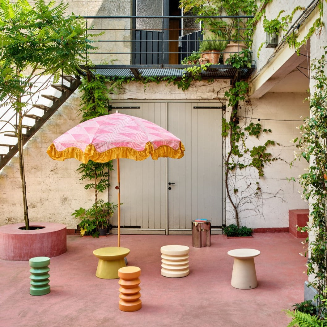 green, terra cream and beige accent tables with pink sun umbrella in back patio yard