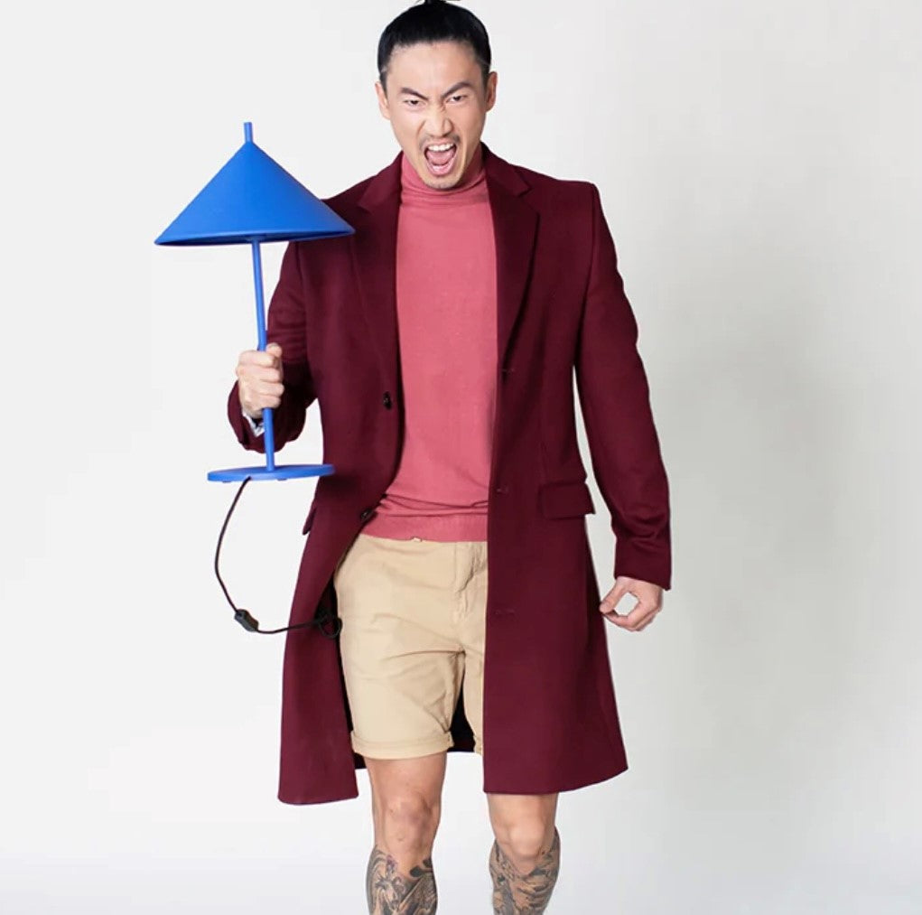 man with maroon colored coat holding a metal blue triangle desk lamp