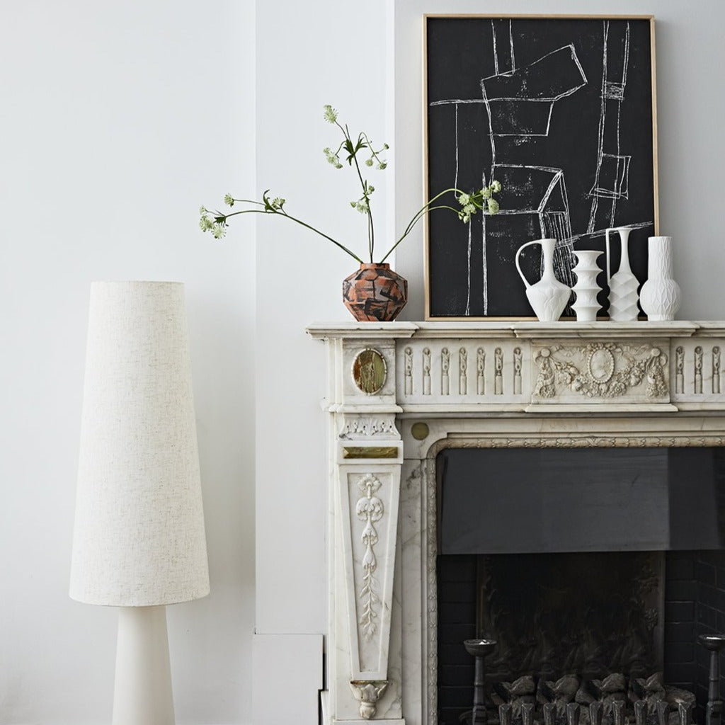 classic fireplace with retro cone floor lamp and black abstract painting