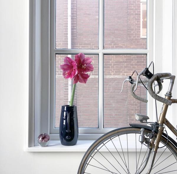 a vase with a face by HK living usa in blue in a window with a bike